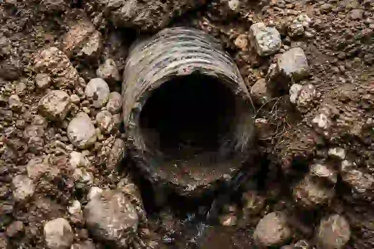 Aging corrugated weeping tile drainage pipe clogged with sediment and restricting groundwater discharge beside an Ontario foundation