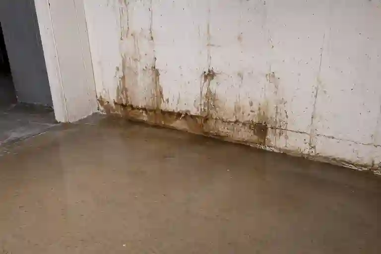 Water-stained basement wall and damp concrete floor caused by inadequate interior drainage in Ontario basement.