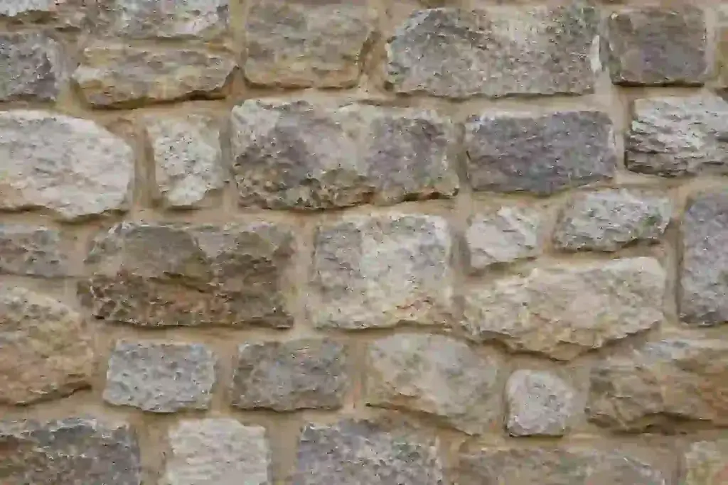 Close-up texture of a traditional stone basement foundation wall with visible mortar joints and irregular natural stone surfaces.
